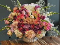 Elegant bouquet of luxury flowers featuring vibrant roses, delicate lilies, and lush greenery arranged in a sleek, modern vase, perfect for upscale events or home décor.