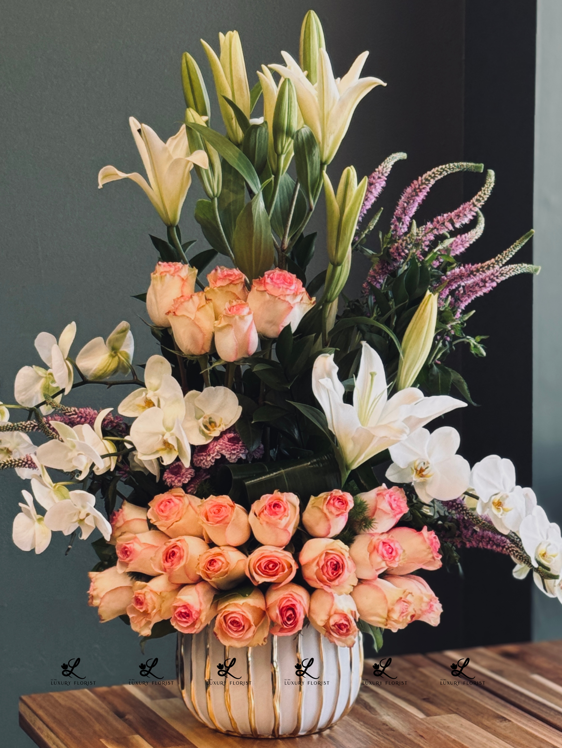 Elegant bouquet of luxury flowers featuring vibrant roses, delicate lilies, and lush greenery arranged in a sleek, modern vase, perfect for upscale events or home décor.